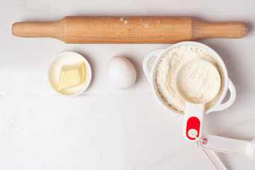 egg, flour and butter and rolling pin on a white background
