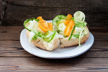 Bruschetta with cream cheese, fresh zuccini slices, yellow tomatoes, herbs and pepper on wooden background. 