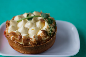Tart with mango passion fruit cream on a white plate. Close-up.