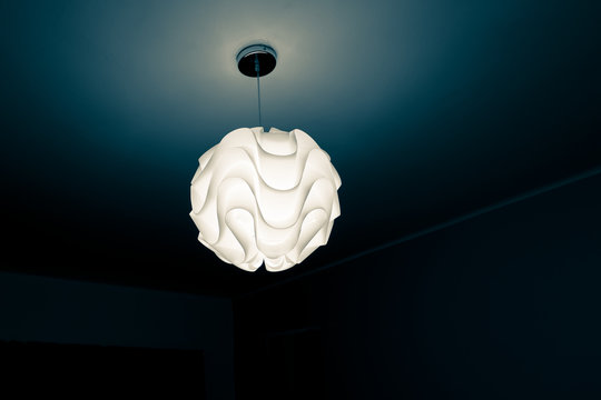 Low Angle View Of Illuminated Light Fixture Hanging From Ceiling In Darkroom