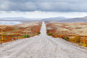 Gravel road to Teriberka in northern tundra landscape of Kola Peninsula. Natural scenery in autumn season. Murmansk Oblast, Russia