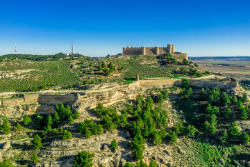 Fototapeta na wymiar Aerial view of Chinchilla de Montearagon castle with ruined excavated inner building remains surrounded by an outer wall with semi circular towers