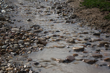 A stream of rainwater running along a stony road