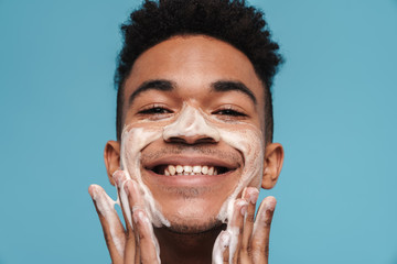 Photo of shirtless african american man applying facial cleanser foam
