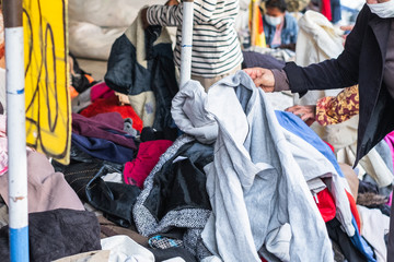 Thai man is choosing used second hand clothes at flea market in Thailand