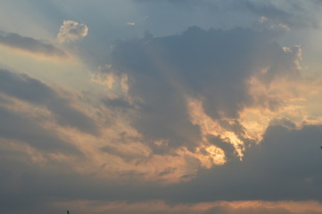 The light of the rising sun in the morning surrounded by clouds.