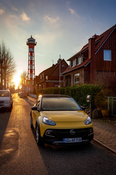 Opel Adam rocks in gelb vor Leuchtfeuer im Sonnenuntergang