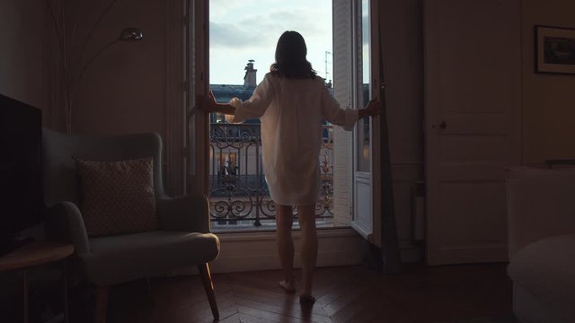 Young girl opening the door to the balcony in Paris