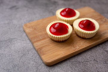 Mini cheesecakes with cherry topping, healthy summer treat on grey stone table