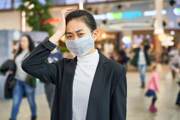 Fototapeta na wymiar Alarmed female wears medical mask to protect, afraid of infection, in shopping center. Concept individual means protection against biological pollution. Deadly coronavirus in China 2019 2020 2019-nCoV