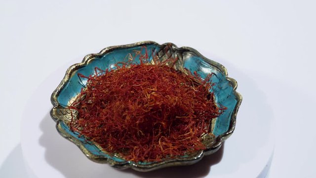 Rotation of bowl with real red saffron spice on white background