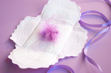 Menstrual pads and tampons on menstruation period calendar with on lilac background.