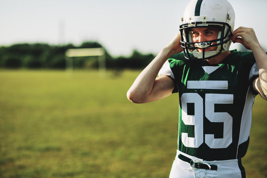 American football player strapping on his helmet during practice