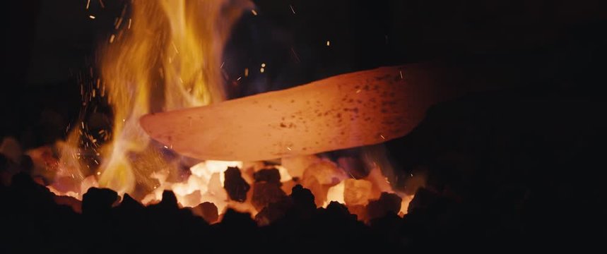 Blacksmith heating iron in fire making knife dark closeup widescreen cinemascope