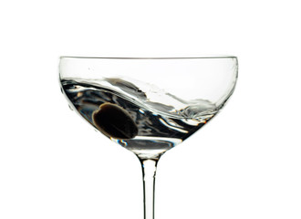 Martini and green olive in glass with splashes isolated on white .