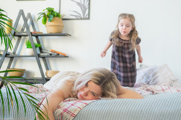 Depressed young mother laying on bed with a child