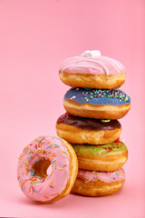 Sweet donuts stacked in a stack on a pink background. Copy space, game of color, sweet life.
