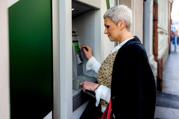 Middle age woman is withdrawing money from ATM machine