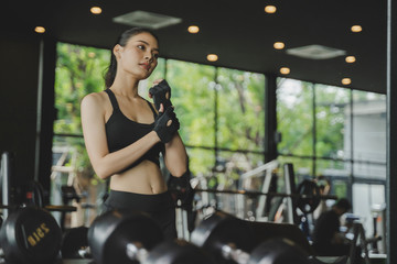 Fototapeta na wymiar athletic young asian pretty slim body woman posing and looking her body in the mirror with machine in fitness gym, bodybuilder, healthy lifestyle, exercise fitness, workout and sport training concept