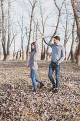 Young couple playing and dancing in the woods in the autumn season