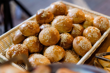 Homemade Hamburger Buns with sesame seeds, laid out in a wicker basket.