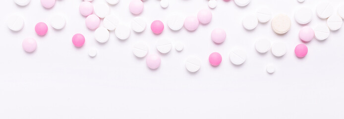Pink and white pills on white background. Heap of assorted various medicine tablets and pills. Horizontal banner.