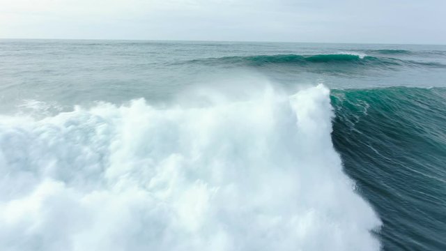 A spectacular flight over a giant ocean wave. A large wave collapses and foams.