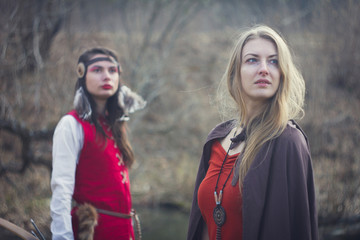 Beautiful girls in long medieval dress near river