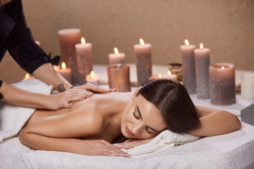 Fototapeta na wymiar beautiful woman receiving massage and aroma theraphy with candles in beauty salon