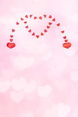 Valentines day or wedding vertical festive pink background with hearts bokeh. Two small hearts merging to one big heart.