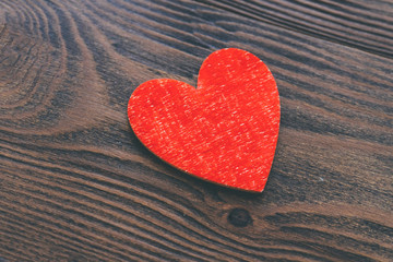 Red colored decorative heart at wooden background. Love concept. Vintage style photo.