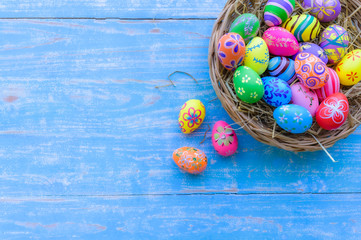 Beautiful colorful easter eggs in wicker basket on blue table wooden