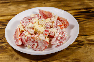 Tasty salad with crab sticks, cheese, tomato and mayonnaise on wooden table