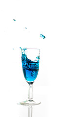 Ein blauer Cocktail schwappt aus einem Sektglas heraus