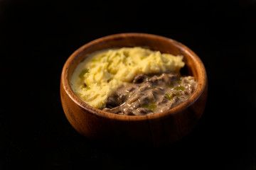 Beef goulash with mashed potatoes in a wooden bowl.