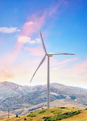 Wind turbine on hill against background of dawn sky