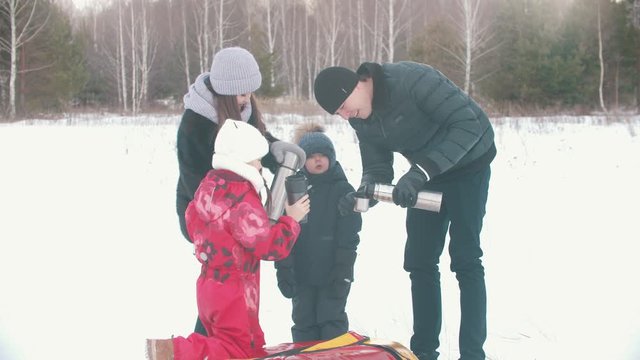 Family drinking tea from the termos outdoors