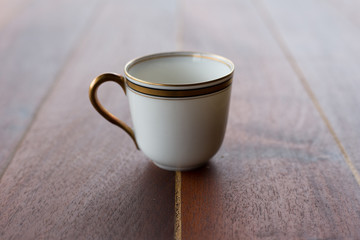 taza blanca con dorado sobre mesa de madera
