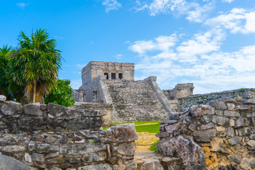 Fototapeta na wymiar Ruins of ancient Tulum. Architecture of ancient maya. View with temple and other old buildings, houses. Blue sky and lush greenery of nature. travel photo. Wallpaper or background. Yucatan. Mexico.