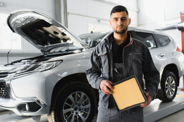 Man holding dirty filter near car at workshop