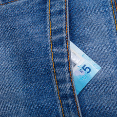 Closeup of five pounds sterling banknote peeking out of blue jeans back pocket