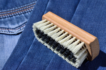 a clothes brush lies on folded jeans.