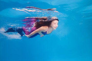 girl in a mermaid costume poses underwater in a pool. - obrazy, fototapety, plakaty