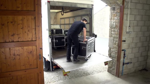 Roadie / Stage Crew unloading Flightcase Trunk from the Truck for a Gig - The Stage Hand is unpacking the equipment.