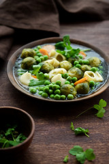 Seasonal Italian minestrone soup with pasta, brussels sprouts, carrots and peas