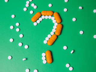 Pills on a blue background. question sign. Suicide. Death from improper treatment. Dangerous drugs. Copy space. View from above.