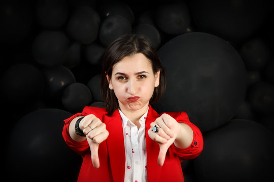 Young woman with a sad face extended her arms with thumbs down. Everything is bad. girl pouting lips in difficult circumstances