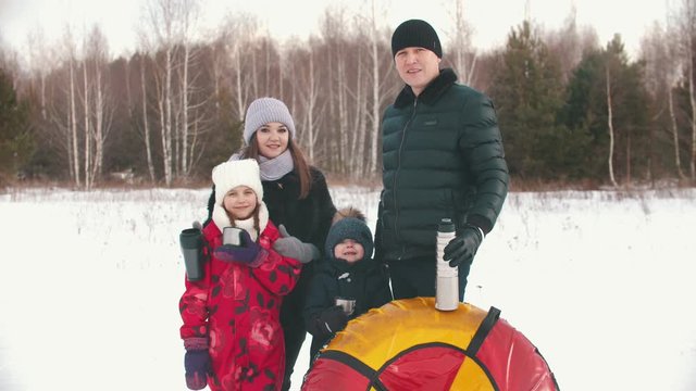 Family standing outdoors holding termos and cups with tea