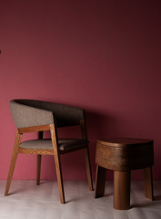Silla de madera de lujo con mesa de madera pulida con tres patas en un espacio con pared rosada y piso en colores crema con luz de la maana