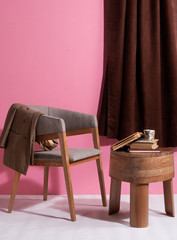 Silla de madera de lujo con mesa de madera pulida con tres patas en un espacio con pared rosada ...